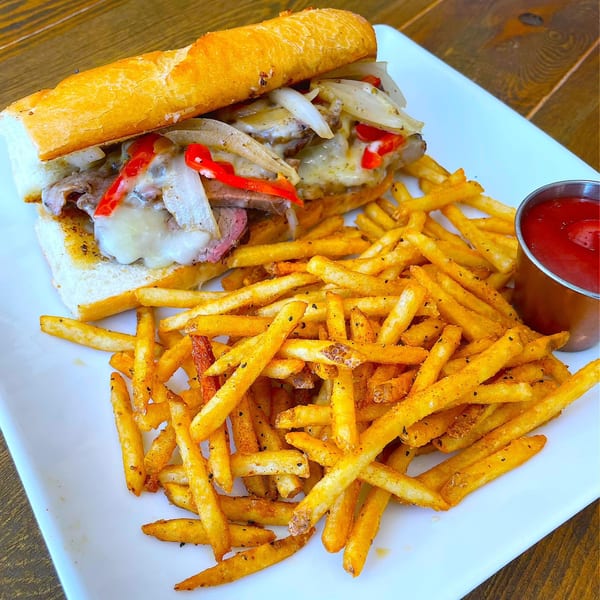 Ribline BBQ's Philly cheesesteak with melted cheese, onions, peppers, and a side of fries.
