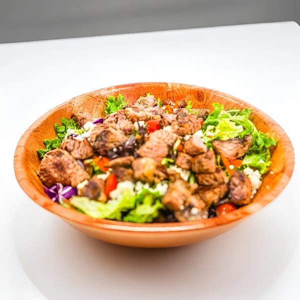 Ribline BBQ's steak salad with lettuce, tomatoes, and crumbled cheese in a wooden bowl.