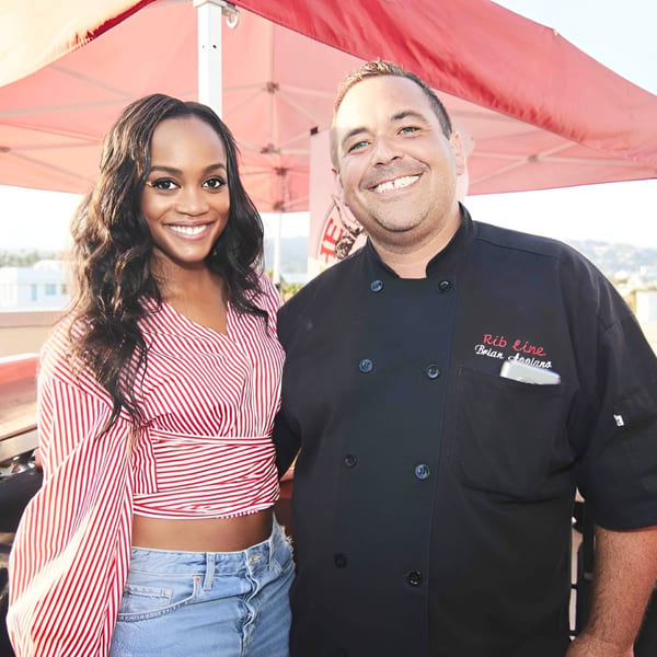 A smiling woman in a red and white striped top next to a chef in a black Ribline uniform.