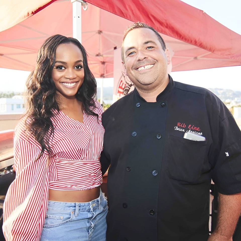 A smiling woman in a red and white striped top next to a chef in a black Ribline uniform.